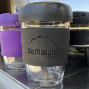 Close up of black keep-cup with branded silicon sleeve and lid